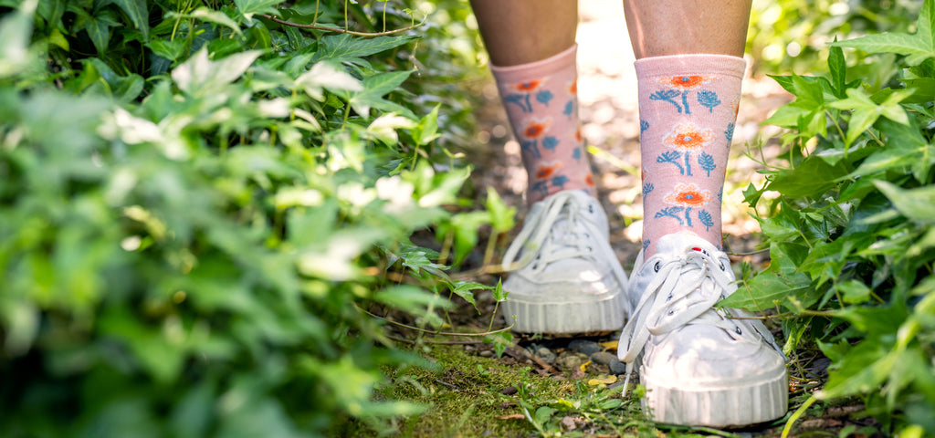 A woman walking through the garden wearing a pair of everyday non-compression sock with a floral pattern.